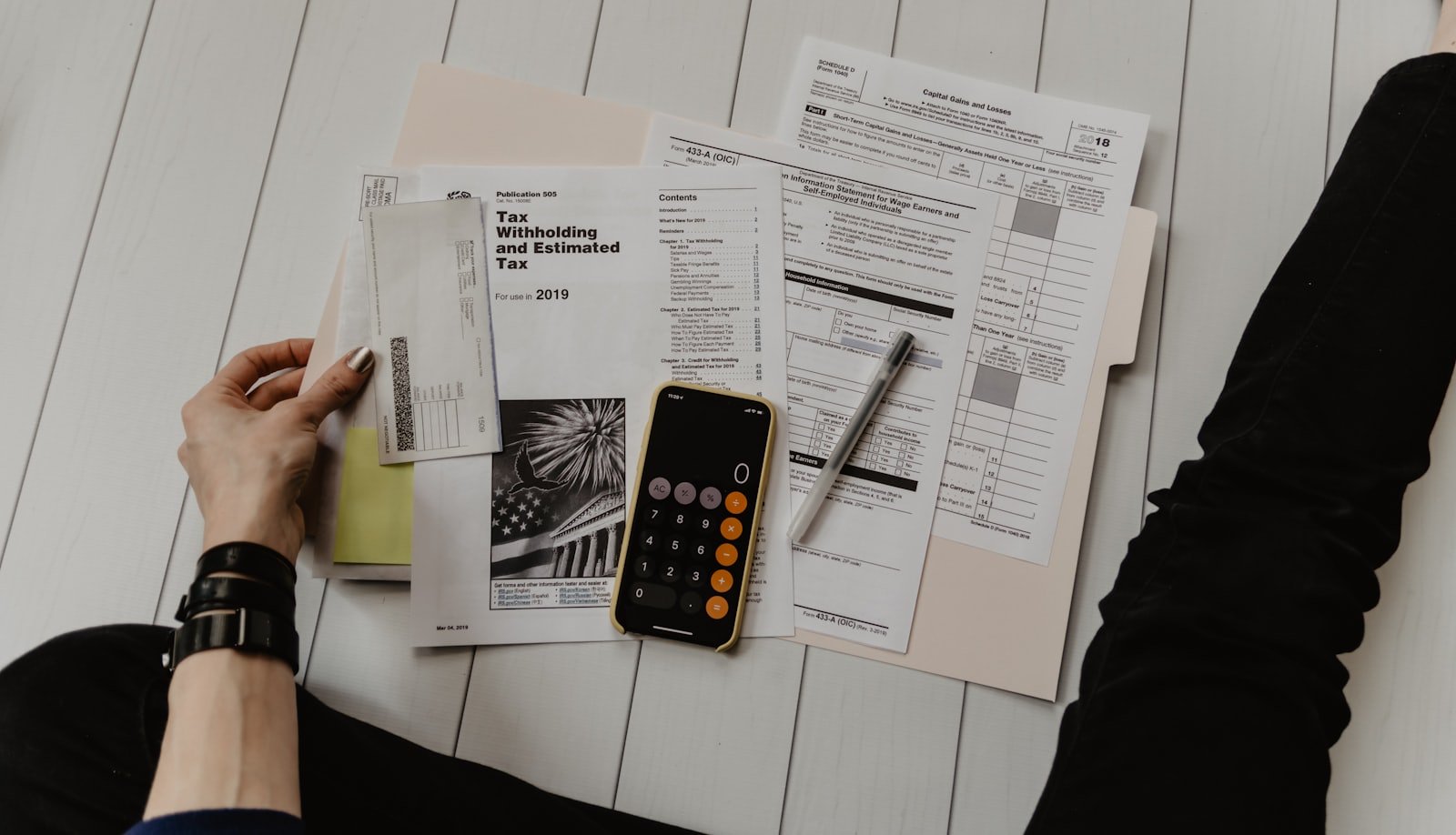 Federal tax forms, a calculator and a pen laid out on a desk during filing season